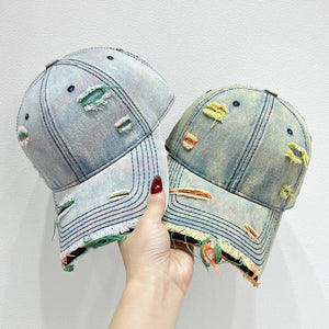 Distressed denim baseball cap with fraying and colorful accents.