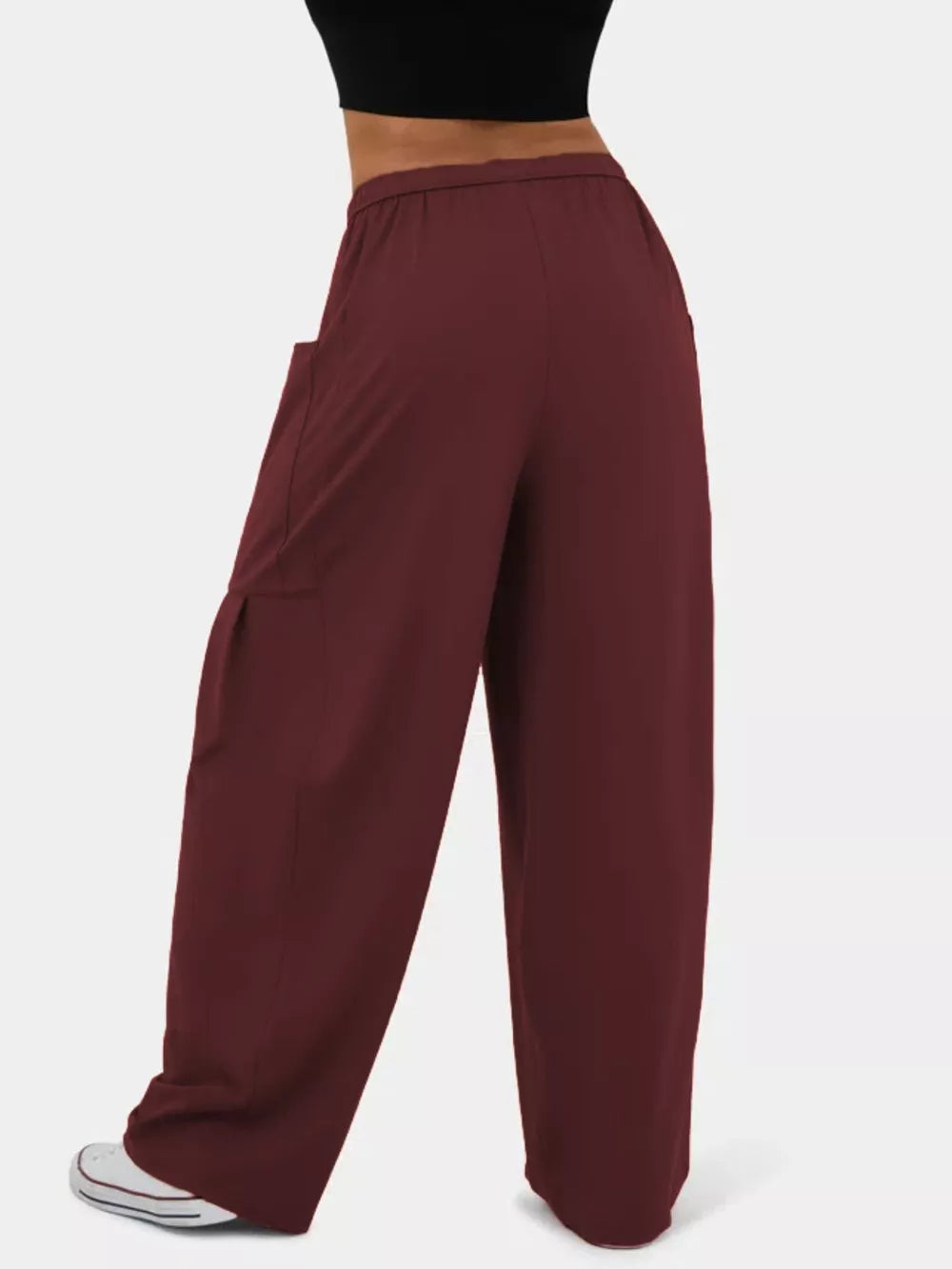Burgundy maternity pants with wide legs and side pockets, styled with a black top and white sneakers.