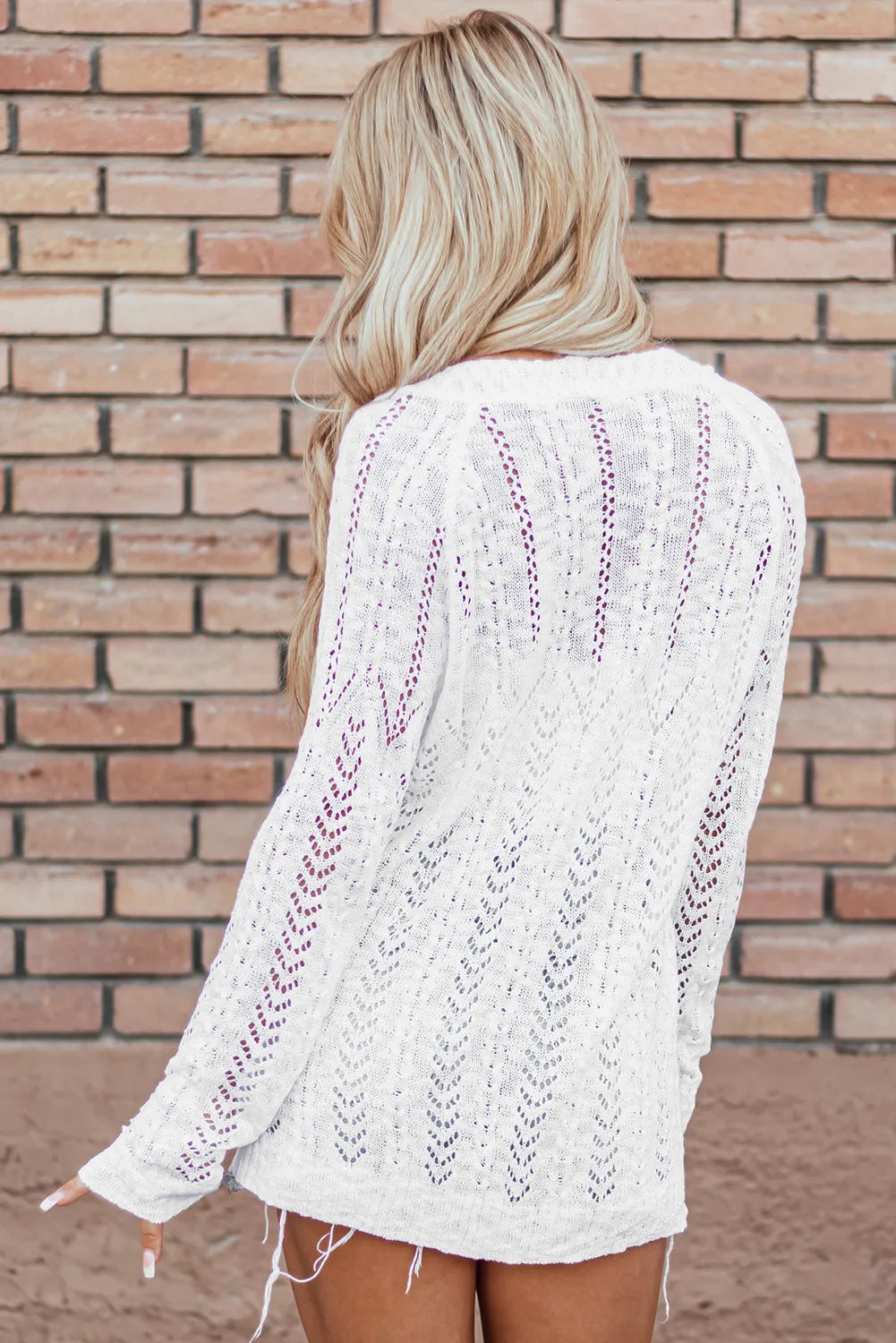 White openwork chevron knit cardigan with open stitch detail and long sleeves.
