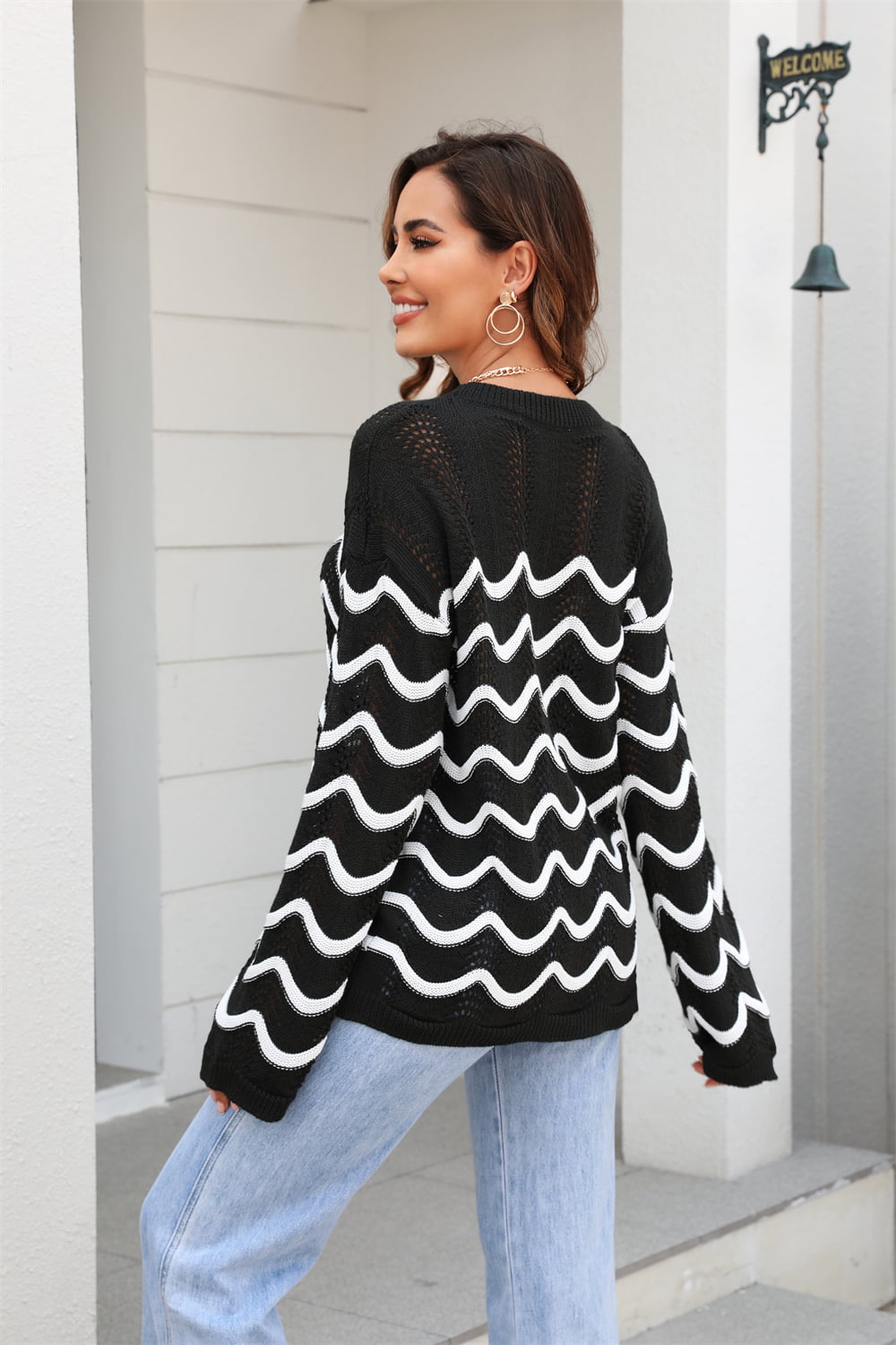 Black wavy knit openwork sweater with white wave pattern and crew neck.