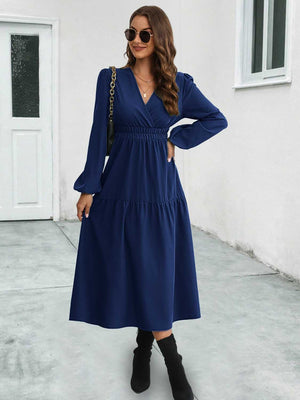Dark blue tiered midi dress with V-neck, long sleeves, and gathered waistline.