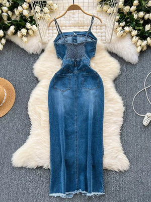 Denim maxi dress with spaghetti straps, smocked bodice, cutout sides, and frayed hem.