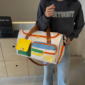 Beige duffel bag with bright colorblock pockets and orange trim, brown straps