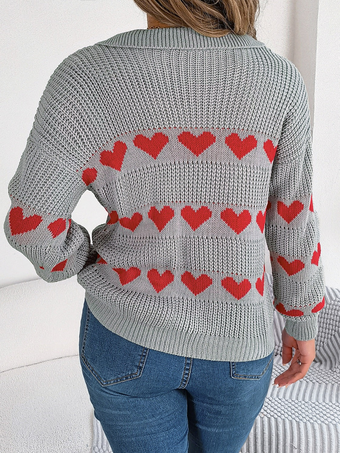 Gray knit polo sweater with red heart stripe pattern and long sleeves.