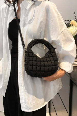 Black padded crescent crossbody bag with sculptural texture and top handle.