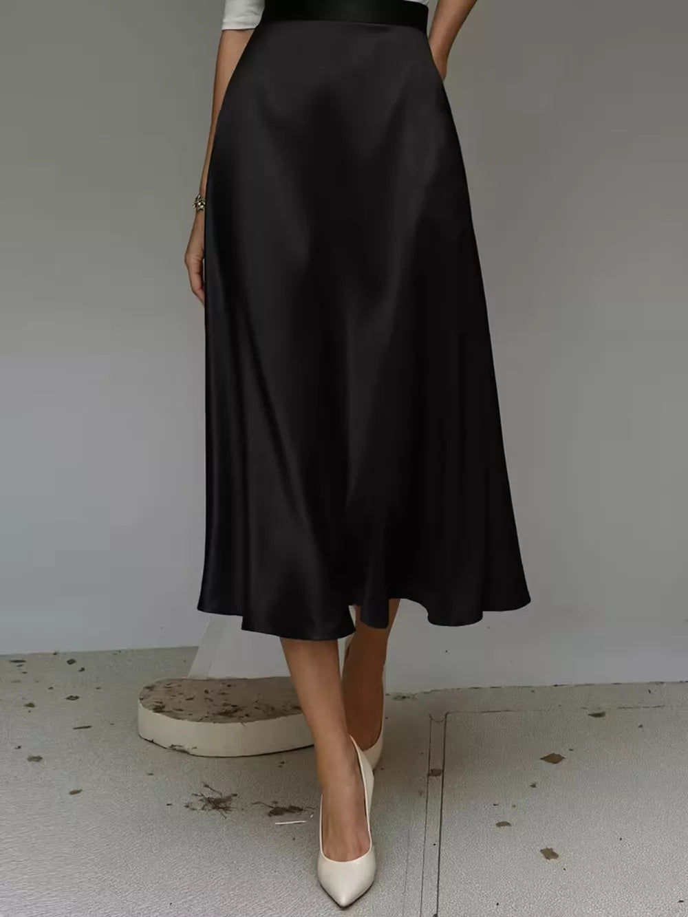 Black satin A-line skirt with pockets, midi length, flowing silhouette.