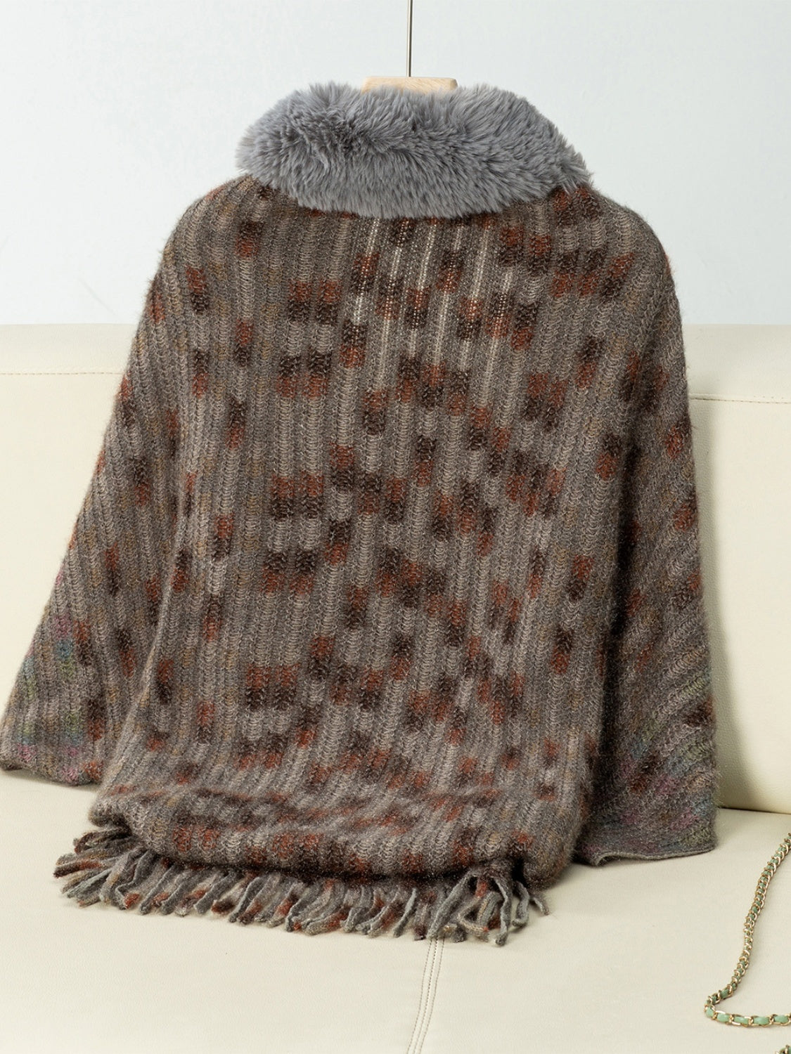 Textured plaid acrylic poncho with faux fur collar and fringe hem in brown tones.