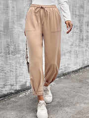 Beige tapered hem utility joggers with drawstring waist and front pockets, styled with white sneakers.