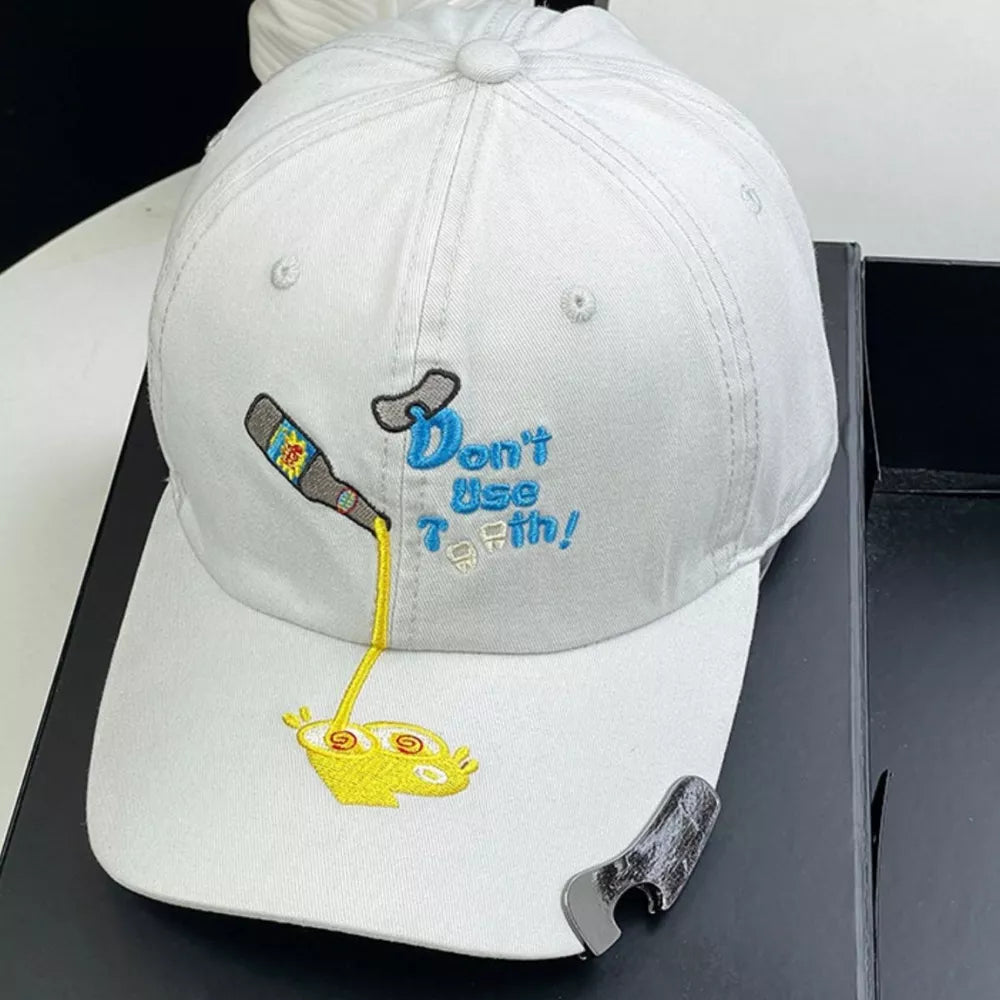 White baseball cap with embroidered cartoon and text.