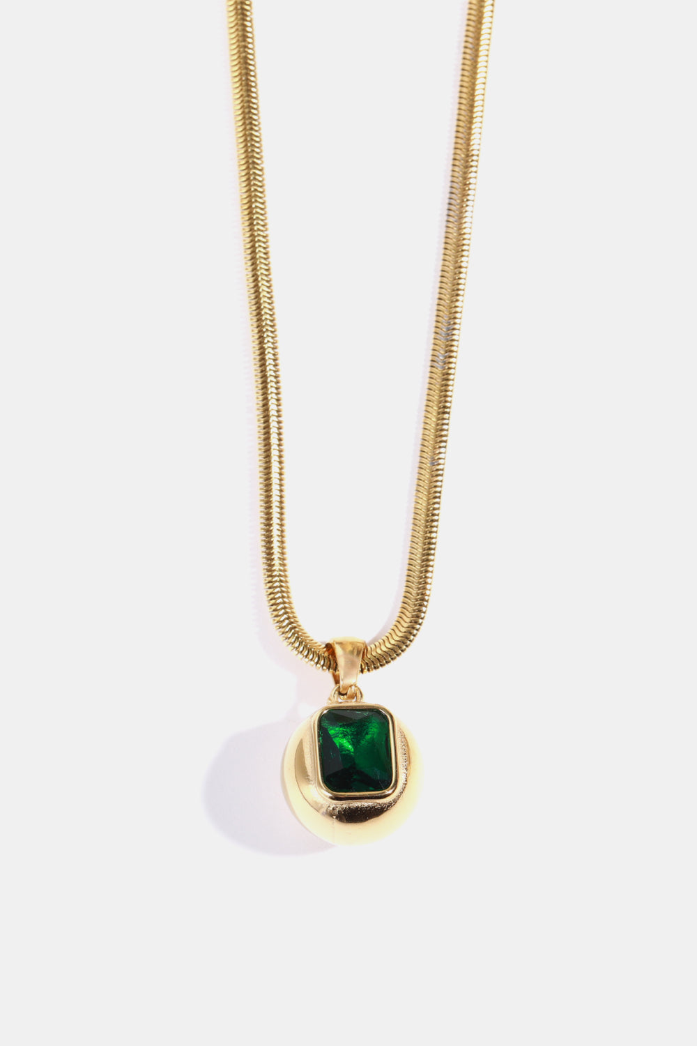 Gold necklace with a round pendant featuring a square dark green stone.