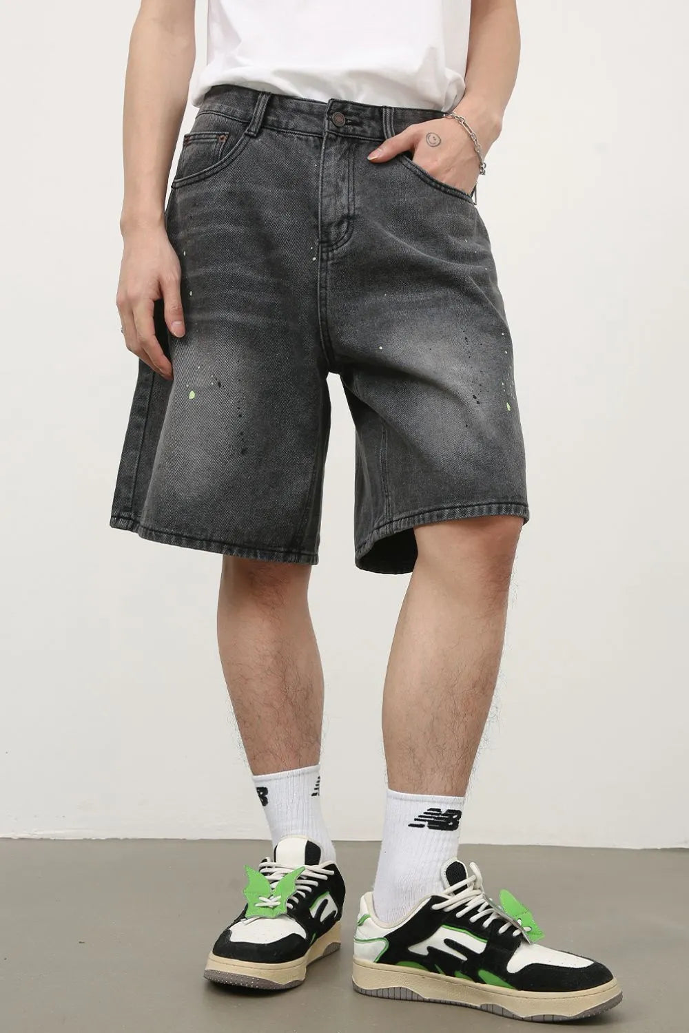 Dark wash denim bermuda shorts with artistic paint splatters and a relaxed fit.
