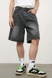 Dark wash denim bermuda shorts with artistic paint splatters and a relaxed fit.
