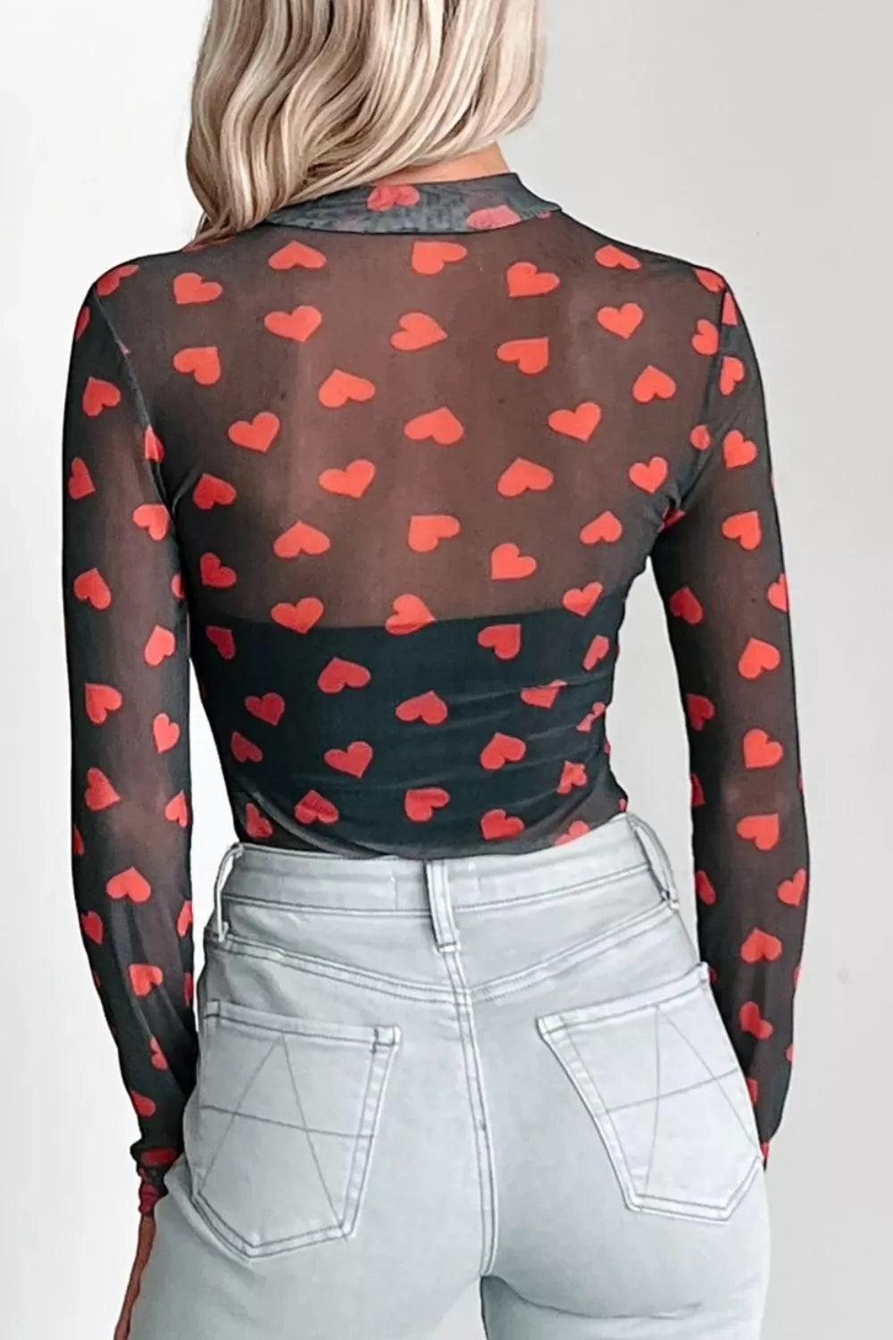 Sheer mesh long sleeve top with allover red heart print and mock neck.