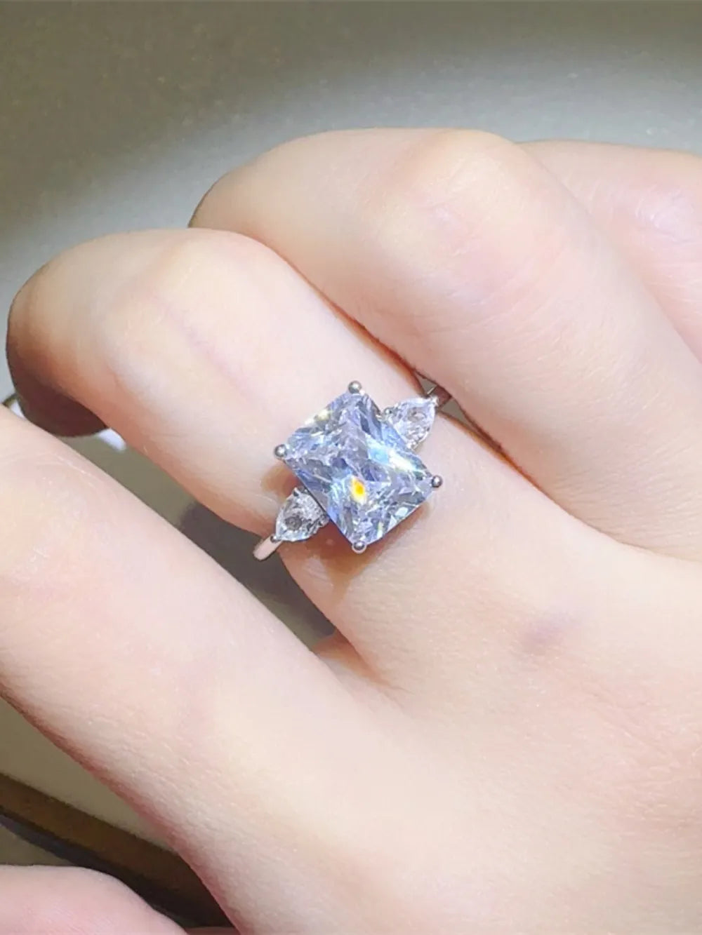 Silver ring with emerald cut center stone and pear accent stones.