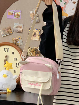 Pink crossbody bag with cat ears and dual front pockets, adjustable strap.
