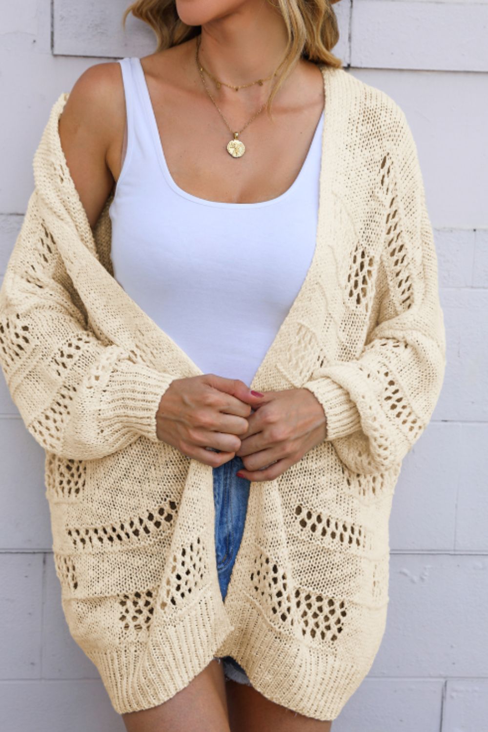 Beige open-knit slouch cardigan with airy cutout details and balloon sleeves.