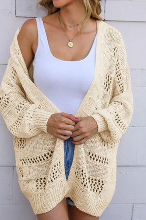 Beige open-knit slouch cardigan with airy cutout details and balloon sleeves.