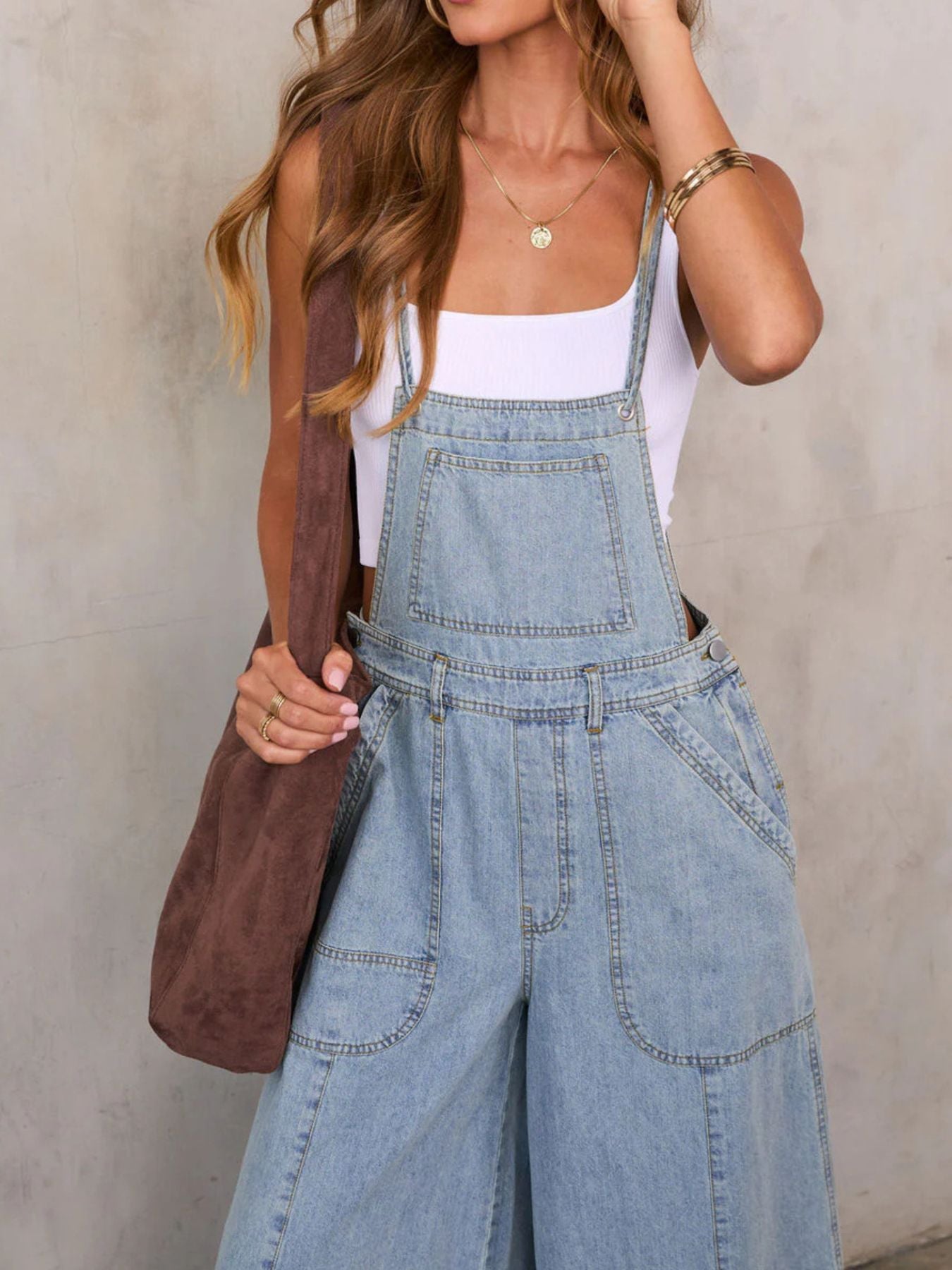 Light wash denim overalls with adjustable straps, bib pocket, and wide legs.