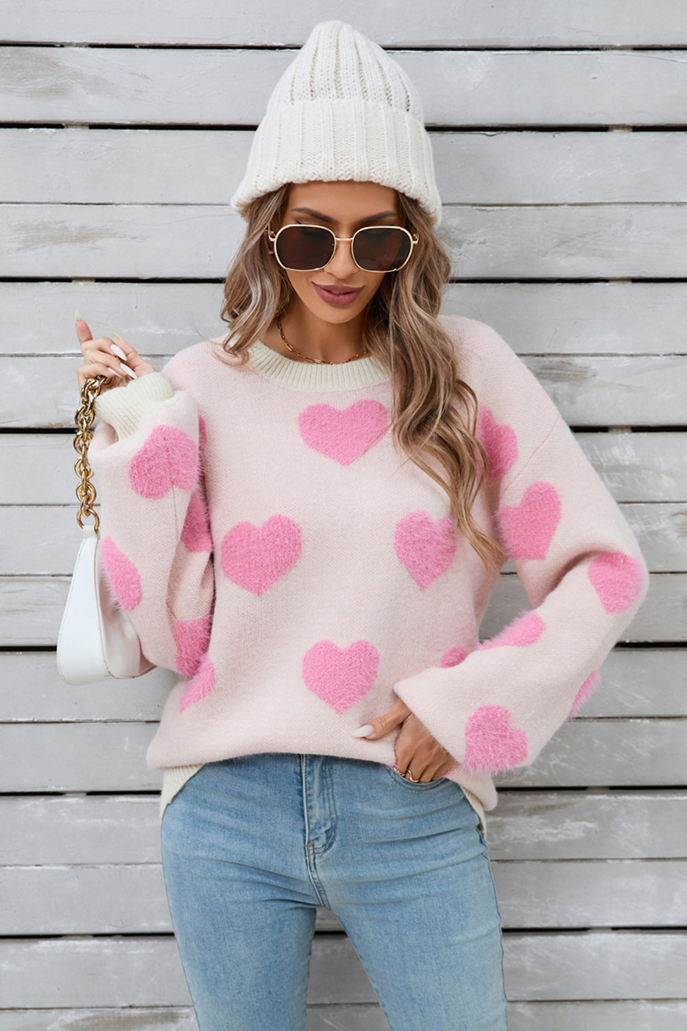 Blush pink fluffy knit sweater with pink heart pattern, crewneck, and long sleeves.