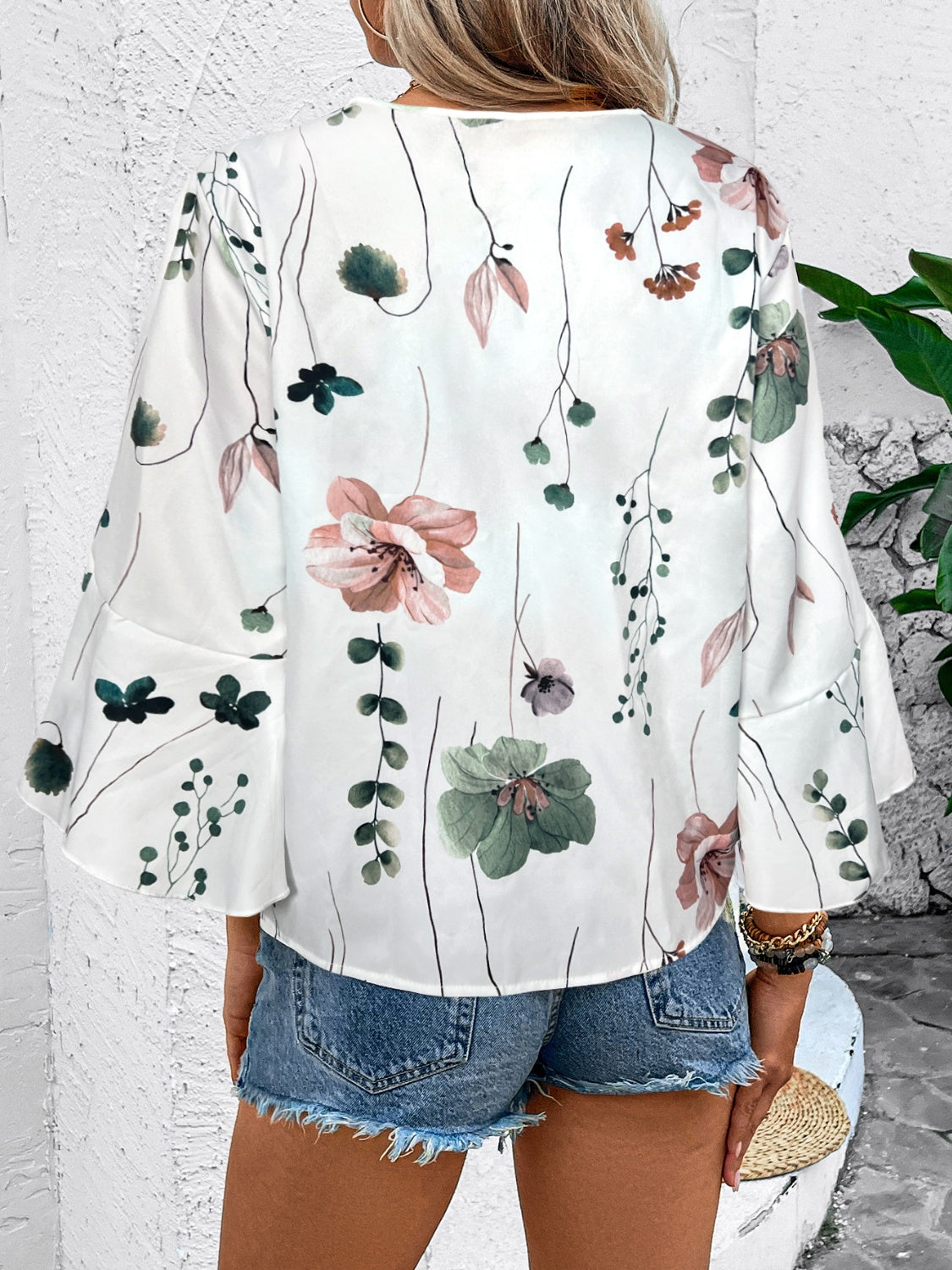 White floral bell sleeve blouse with lace trim and a v-neckline.