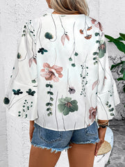 White floral bell sleeve blouse with lace trim and a v-neckline.