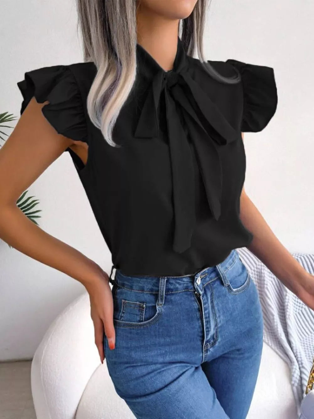 Black pussy-bow blouse with ruffle cap sleeves, styled with blue jeans.