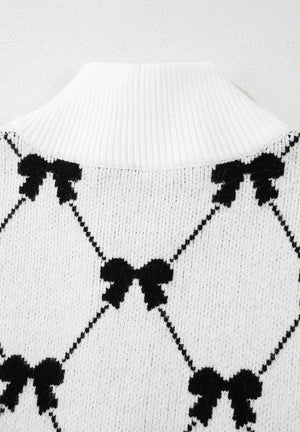 White knit zip vest with black diamond bow pattern and ribbed mock neck.