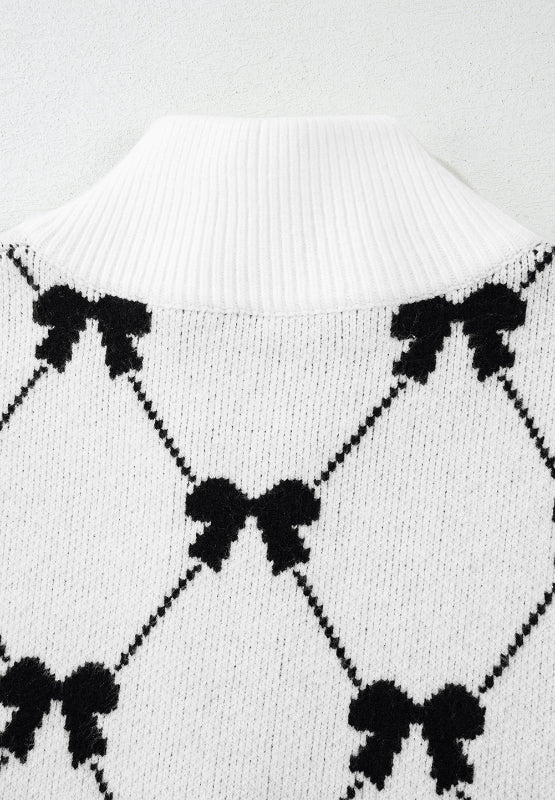White knit zip vest with black diamond bow pattern and ribbed mock neck.