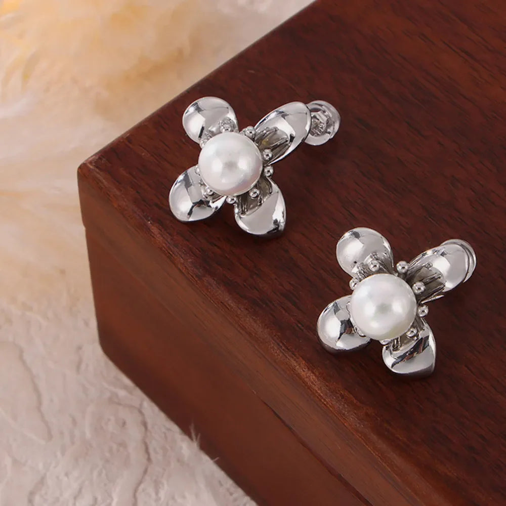 Silver petal pearl stud earrings with a floral design.