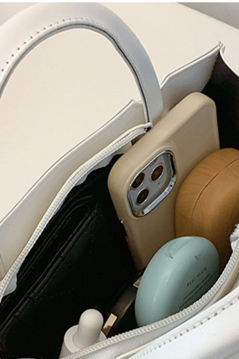 White structured mini bag interior with phone, wallet, and makeup.