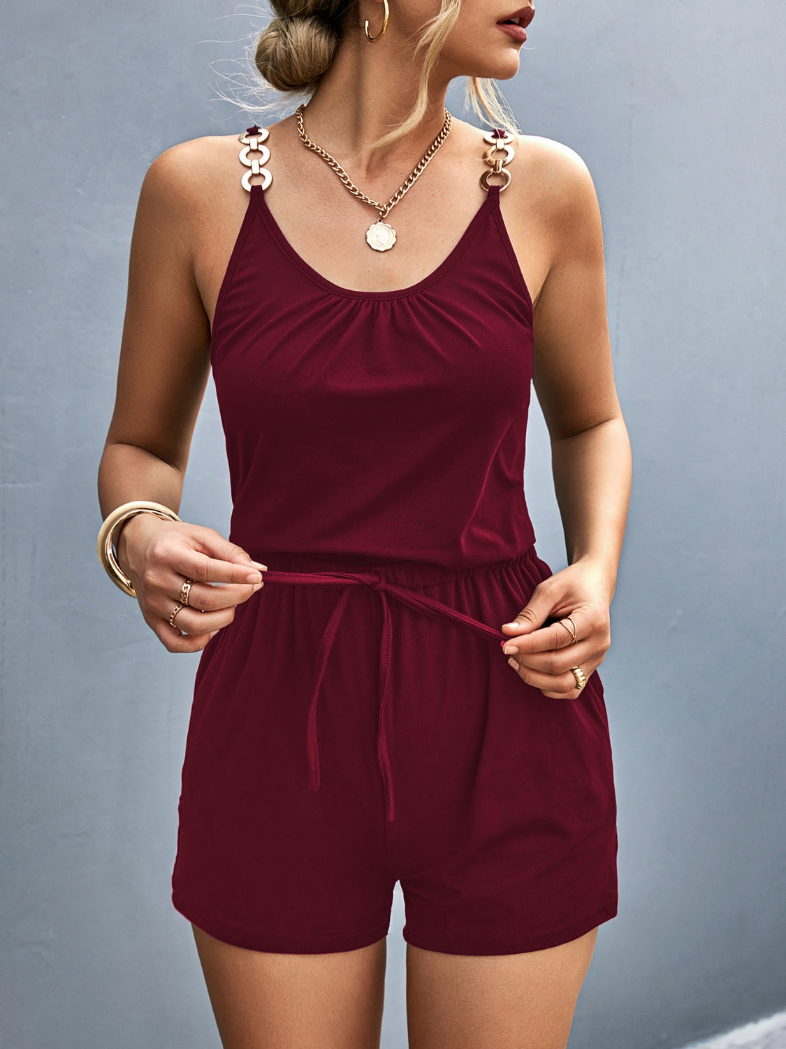 Burgundy chain-strap drawstring romper with ruched neckline and gold-tone hardware.