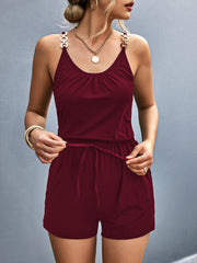 Burgundy chain-strap drawstring romper with ruched neckline and gold-tone hardware.