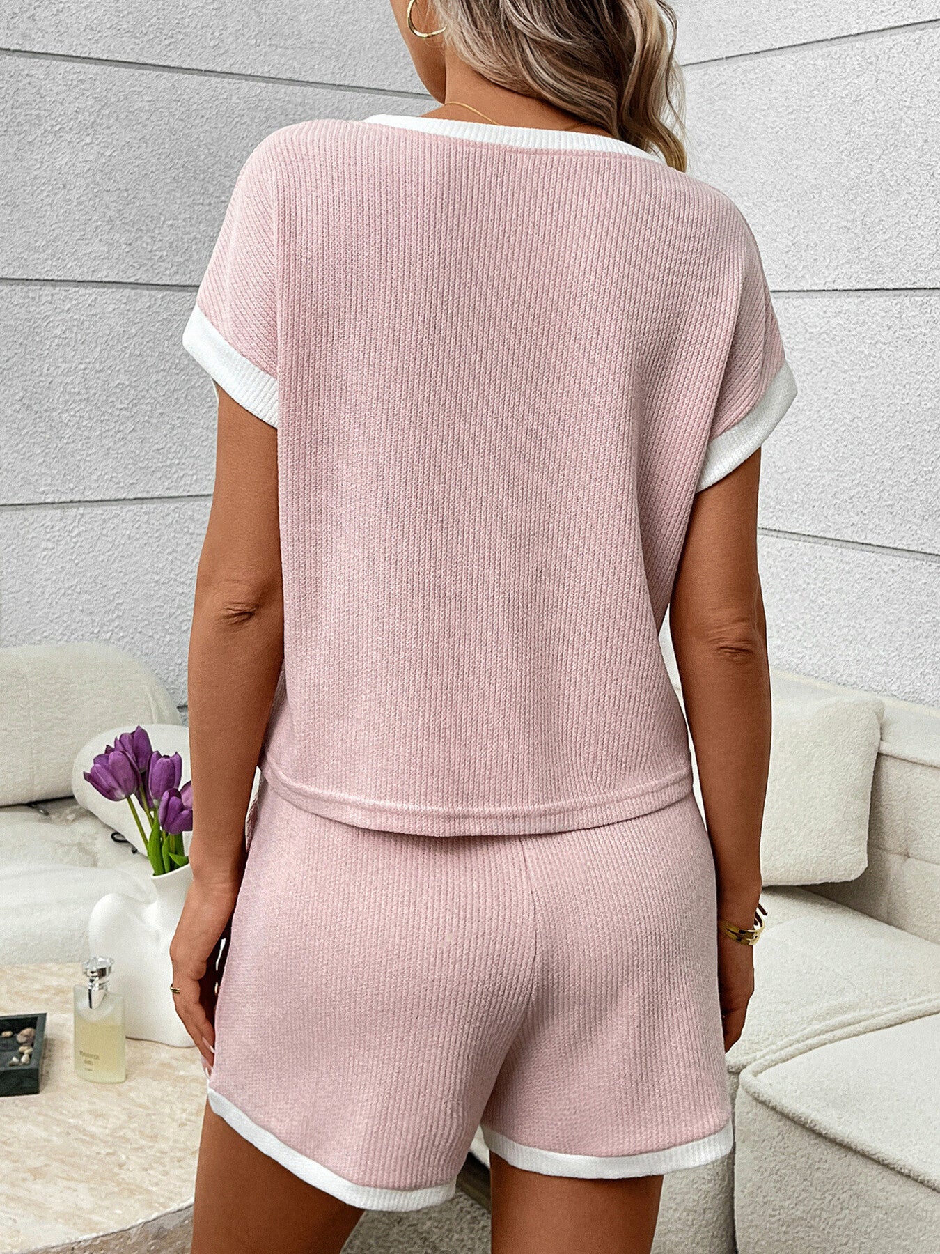 Pink ribbed knit two-piece set with white trim, short sleeves, and shorts.