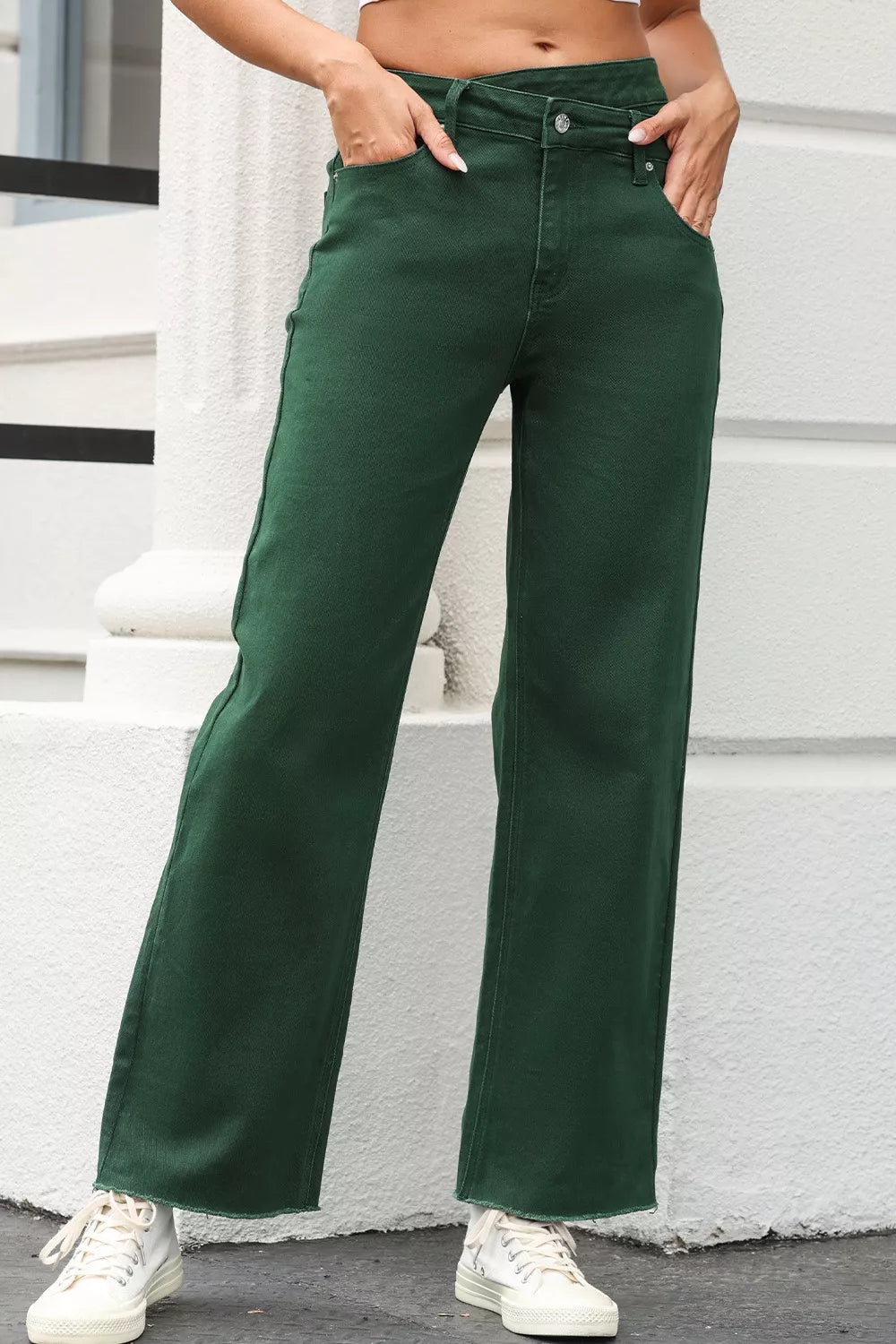 Green cotton jeans with a crossed v-waist and straight leg, featuring a raw hem.