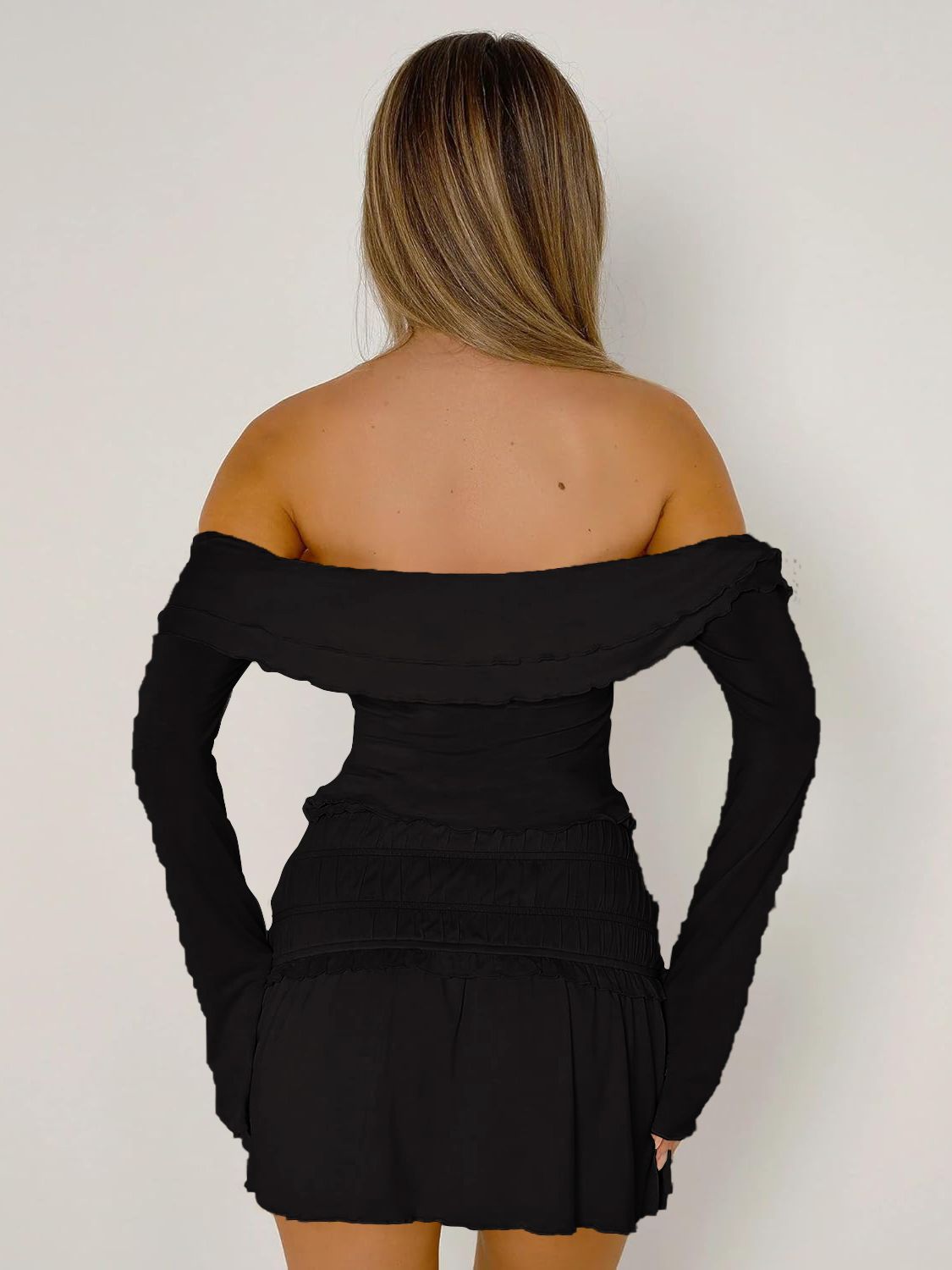 Black off-shoulder ruched bodice top with long sleeves and ruffled neckline.