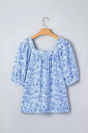 Floral pleated blouse with square neckline and puff sleeves in blue and white print.