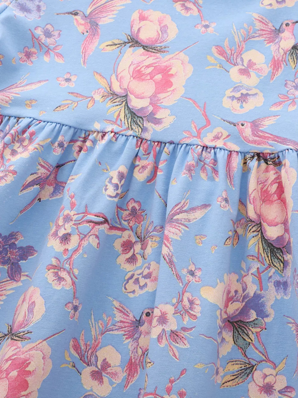 Baby dress with floral hummingbird print on blue cotton blend fabric, featuring a ruffled hem.