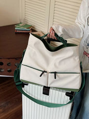 Premium Oxford cloth travel bag in ivory with green trim and straps, featuring two front zip pockets.