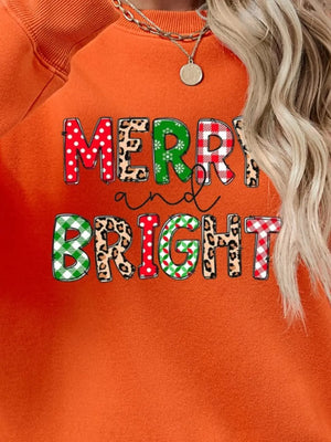 Orange graphic sweatshirt with "Merry and Bright" text in festive patterns like polka dot, leopard, and plaid.