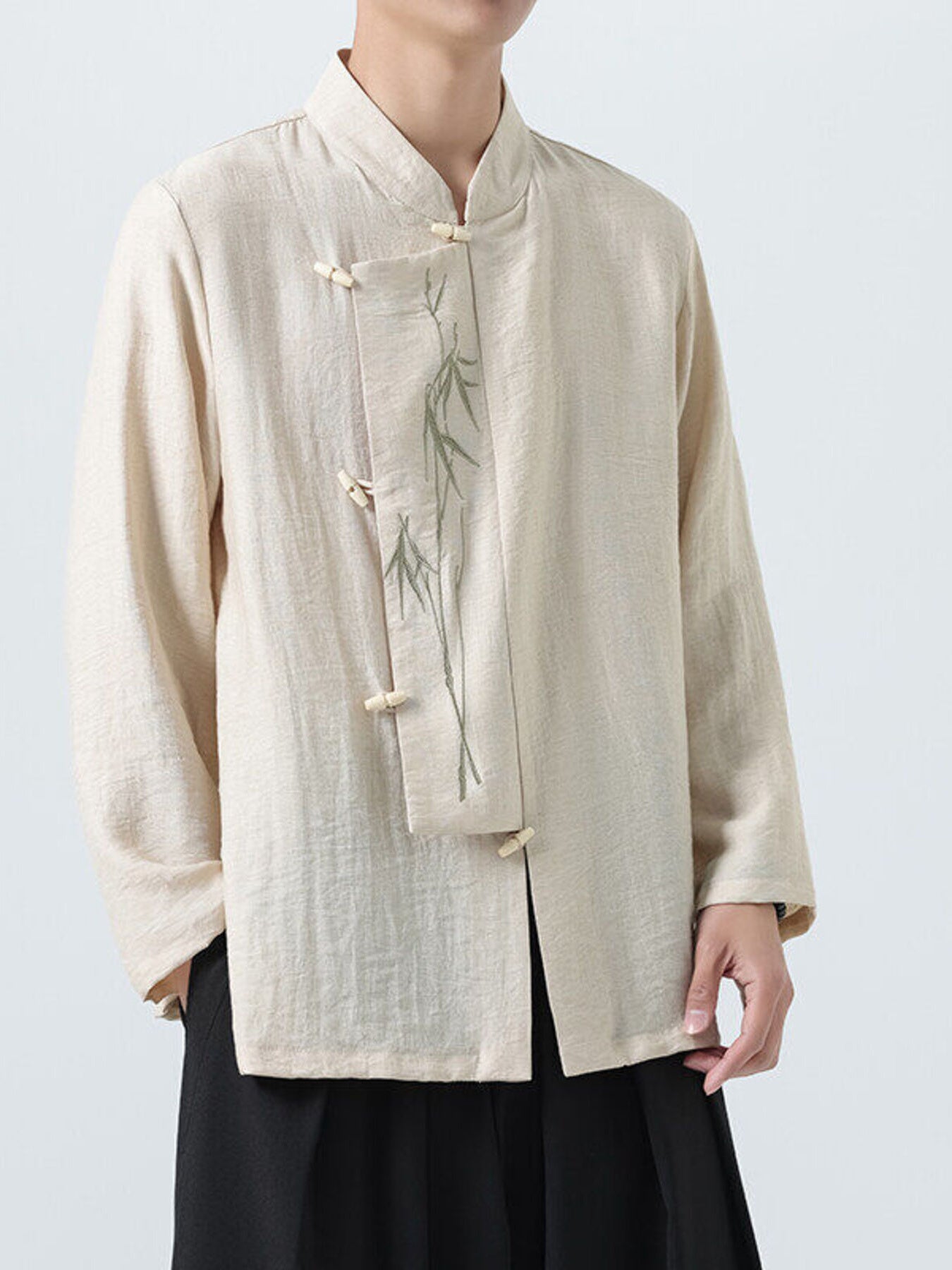 Men's ivory cotton shirt with mandarin collar, bamboo embroidery, and button closure.