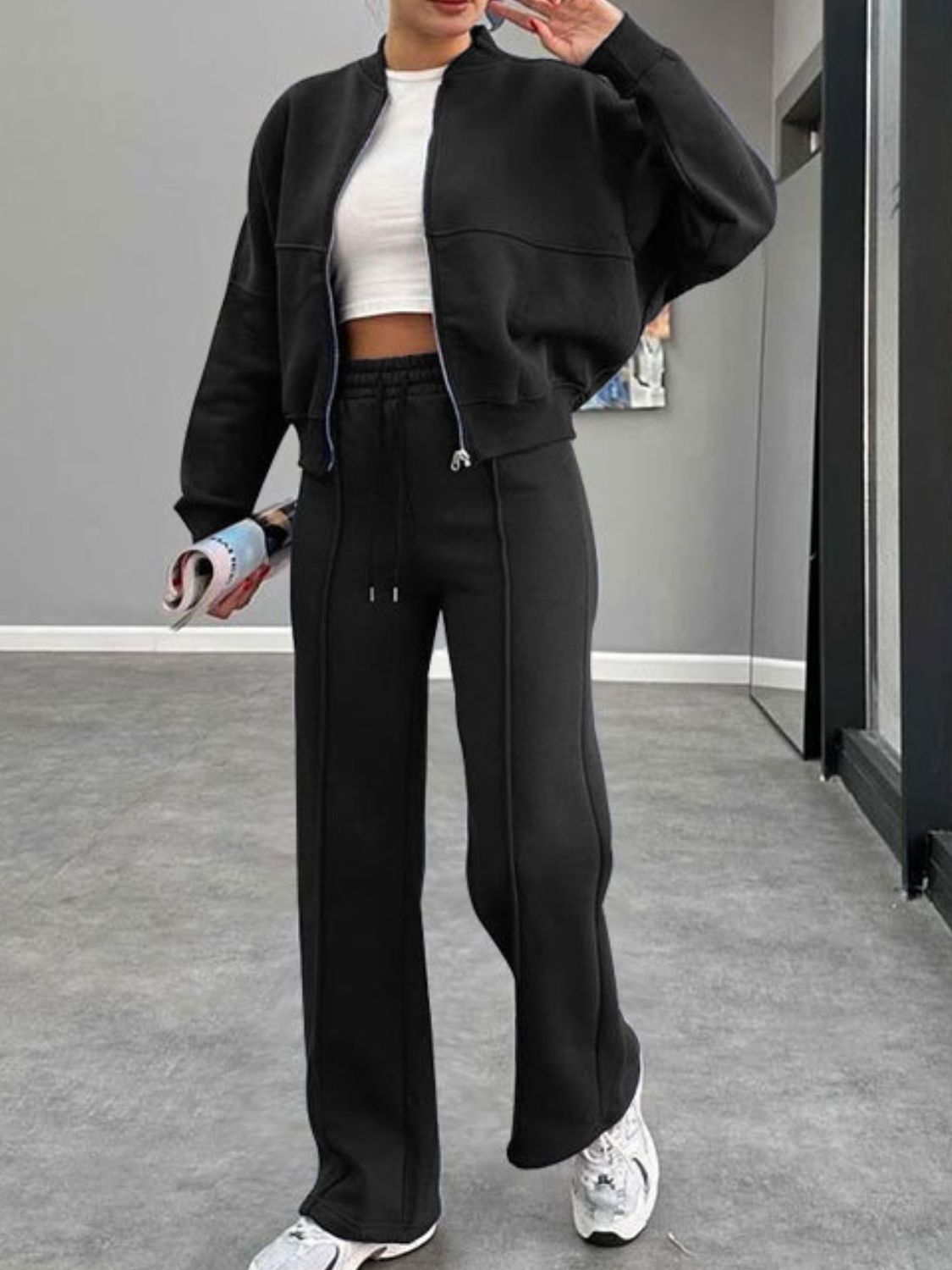 Black bomber jacket and wide-leg tracksuit with drawstring waist and white crop top.