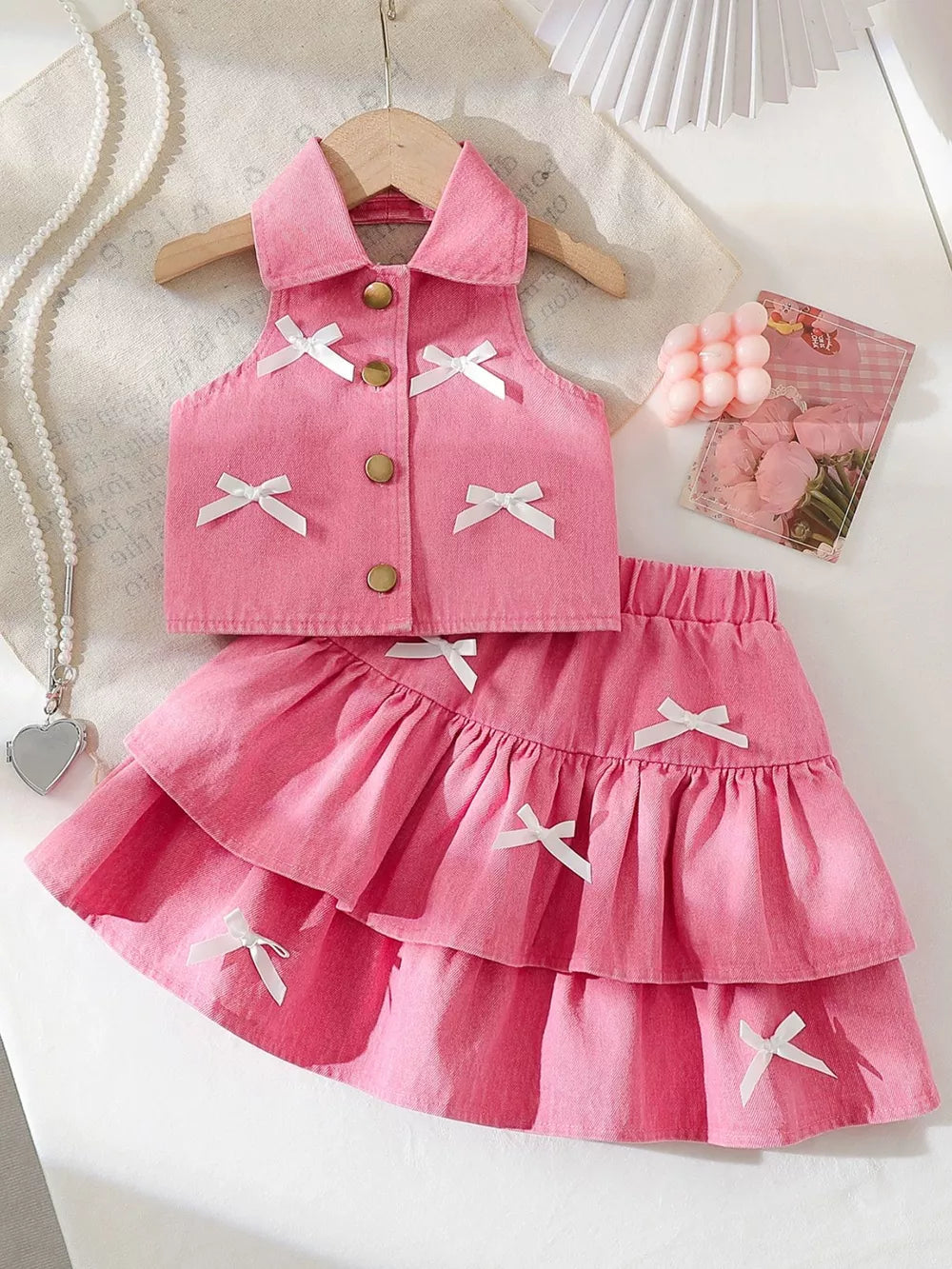 Pink denim halter set with white bow accents and tiered skirt.