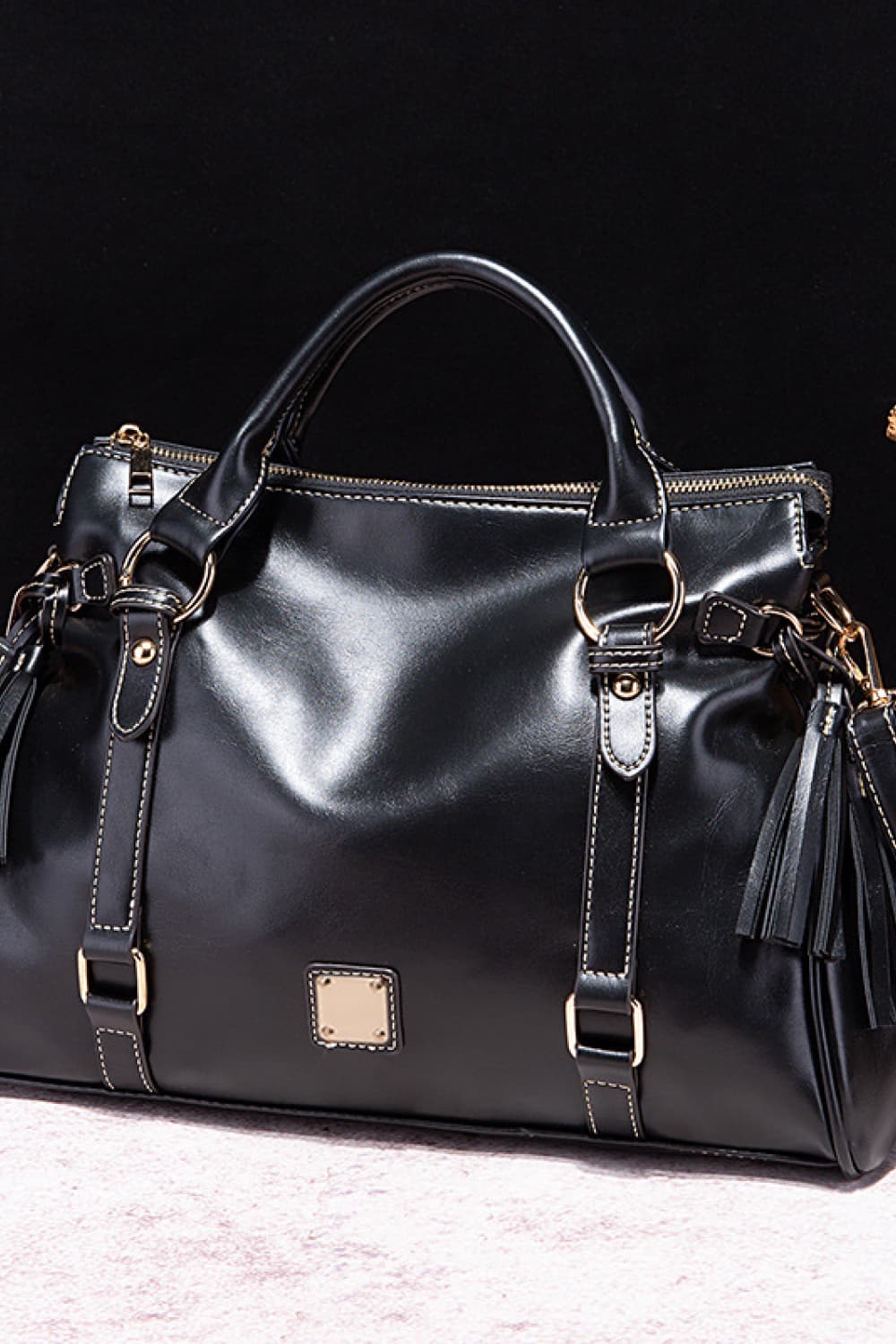 Black structured satchel bag with gold hardware and tassel details