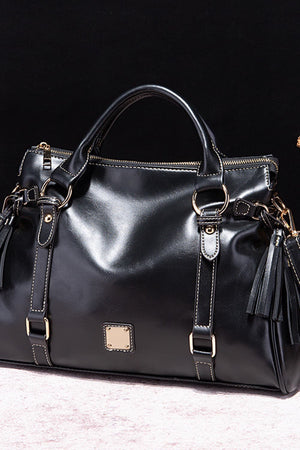 Black structured satchel bag with gold hardware and tassel details