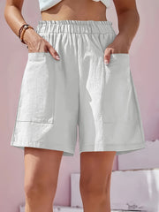 White relaxed fit utility shorts with elastic waist and large cargo pockets.