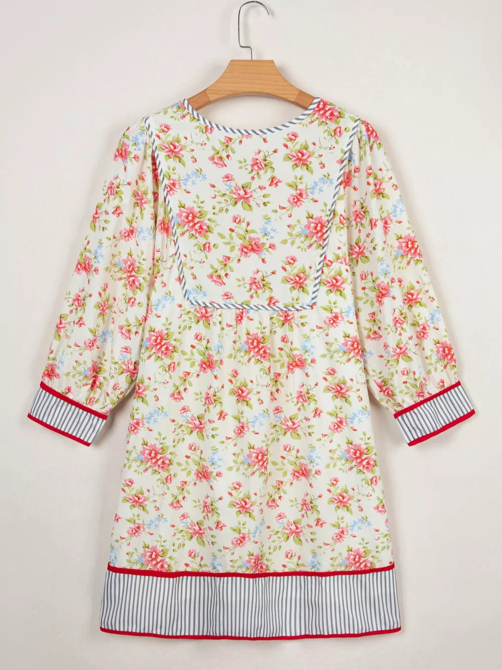 Floral cotton dress with puff sleeves, contrast trim, and striped hem.