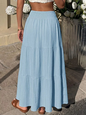 Blue smocked tiered maxi skirt with flowing elegance and textured fabric.
