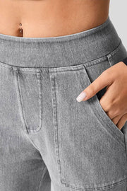 Utility denim wide-leg trousers in gray with a hand in the pocket.