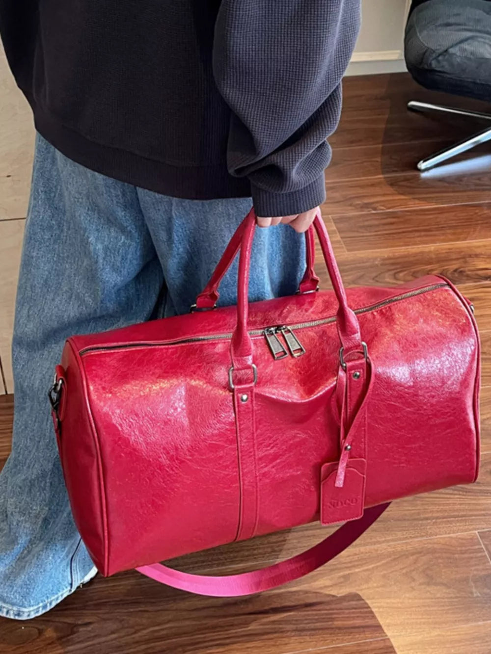 Textured metallic duffle bag in wine red with double zip closure and detachable strap.