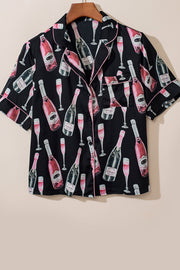 Black silk pajama top with champagne bottle and glass print, pink piping, and short sleeves.